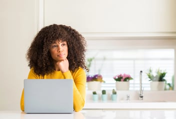 African american woman using computer laptop at kitchen serious face thinking about question, very confused idea