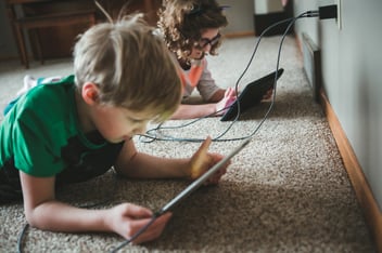 Children using tablets plugged into a dual charger