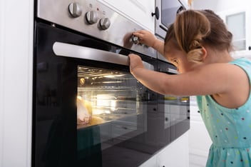 Close-up Of Girl's Hand Touching Electric Oven