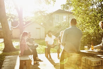 Group of friends sitting in backyard on sunny summer evening