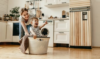 Happy family mother housewife and child   in laundry with washing machine