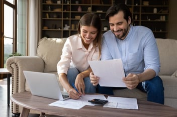 Happy young family couple managing household budget.