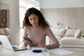 Latino woman pay bills on cell calculate on machine