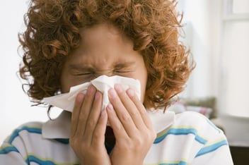 Mixed Race boy blowing nose