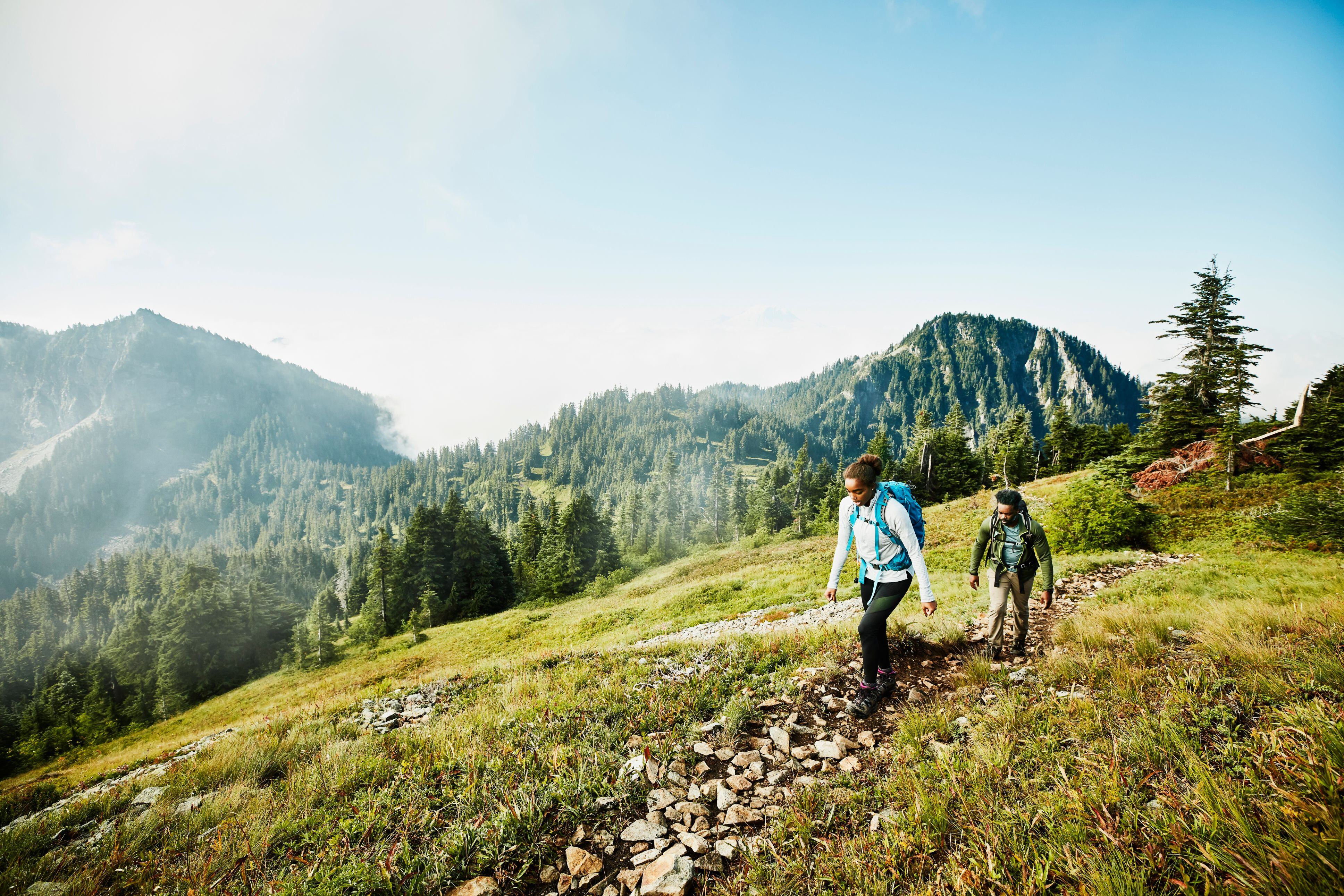 Daughter leading father on morning hike up mountainside