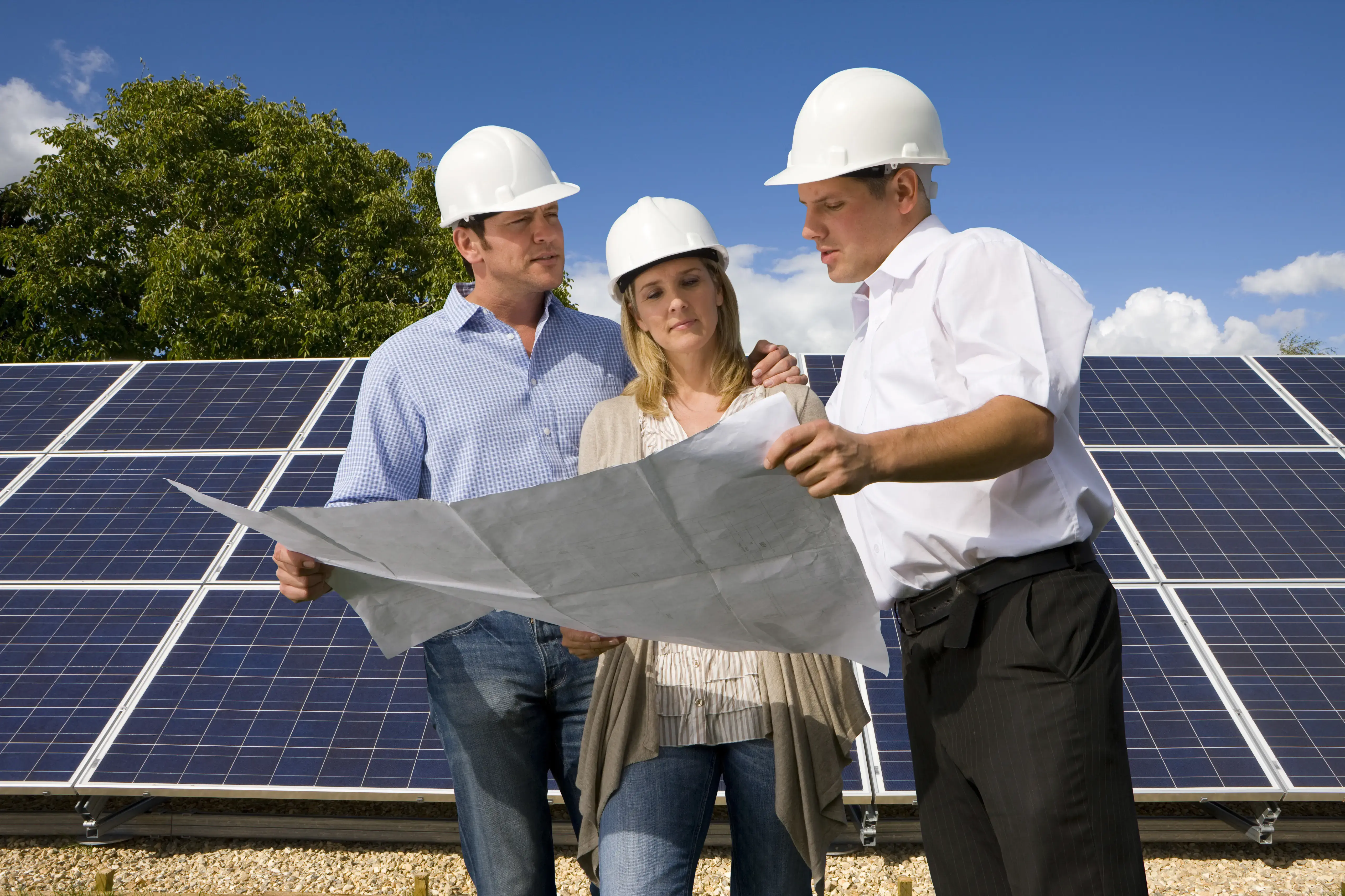 Engineers looking at plans standing next to large solar panels