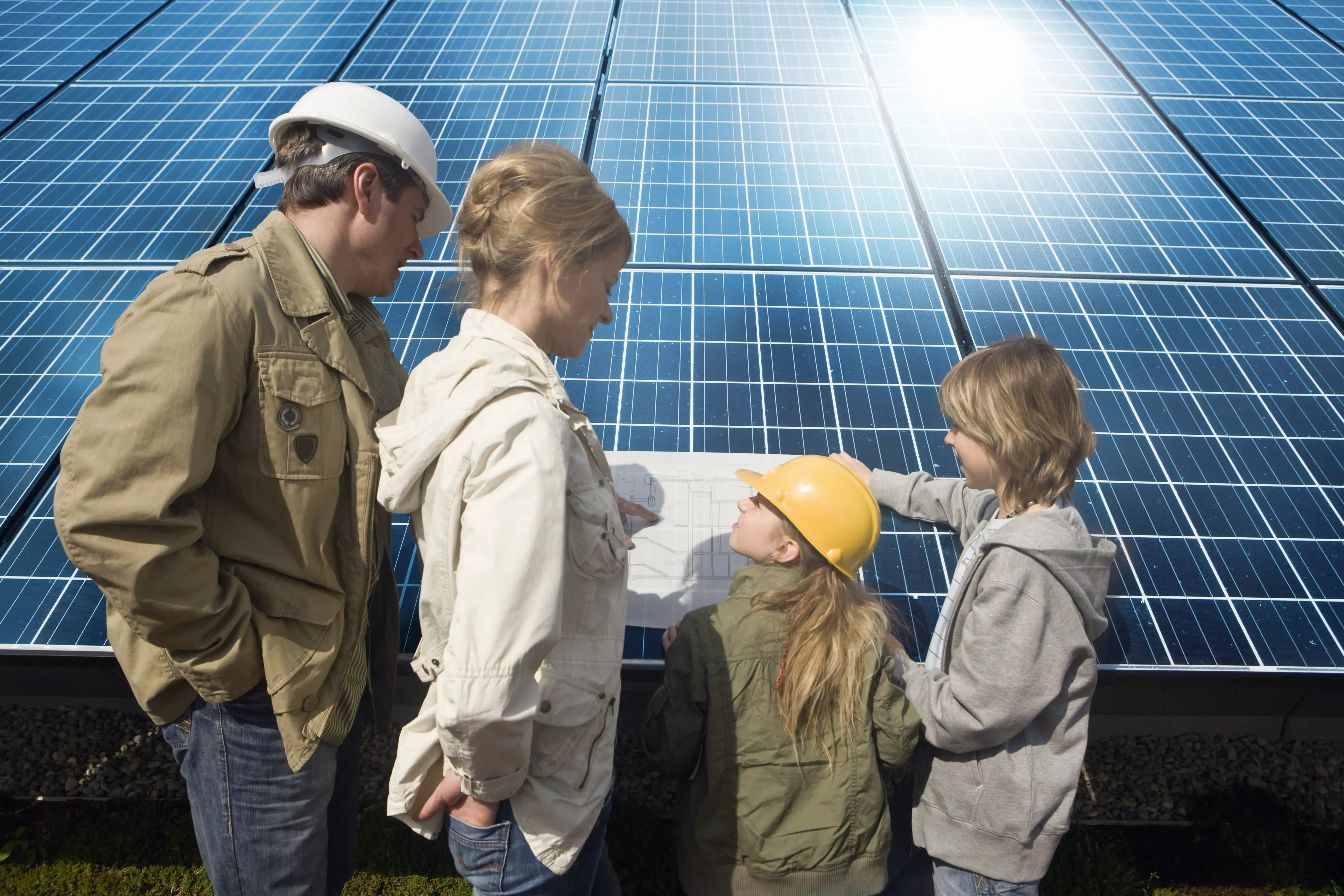 Family standing by solar panels looking at plans