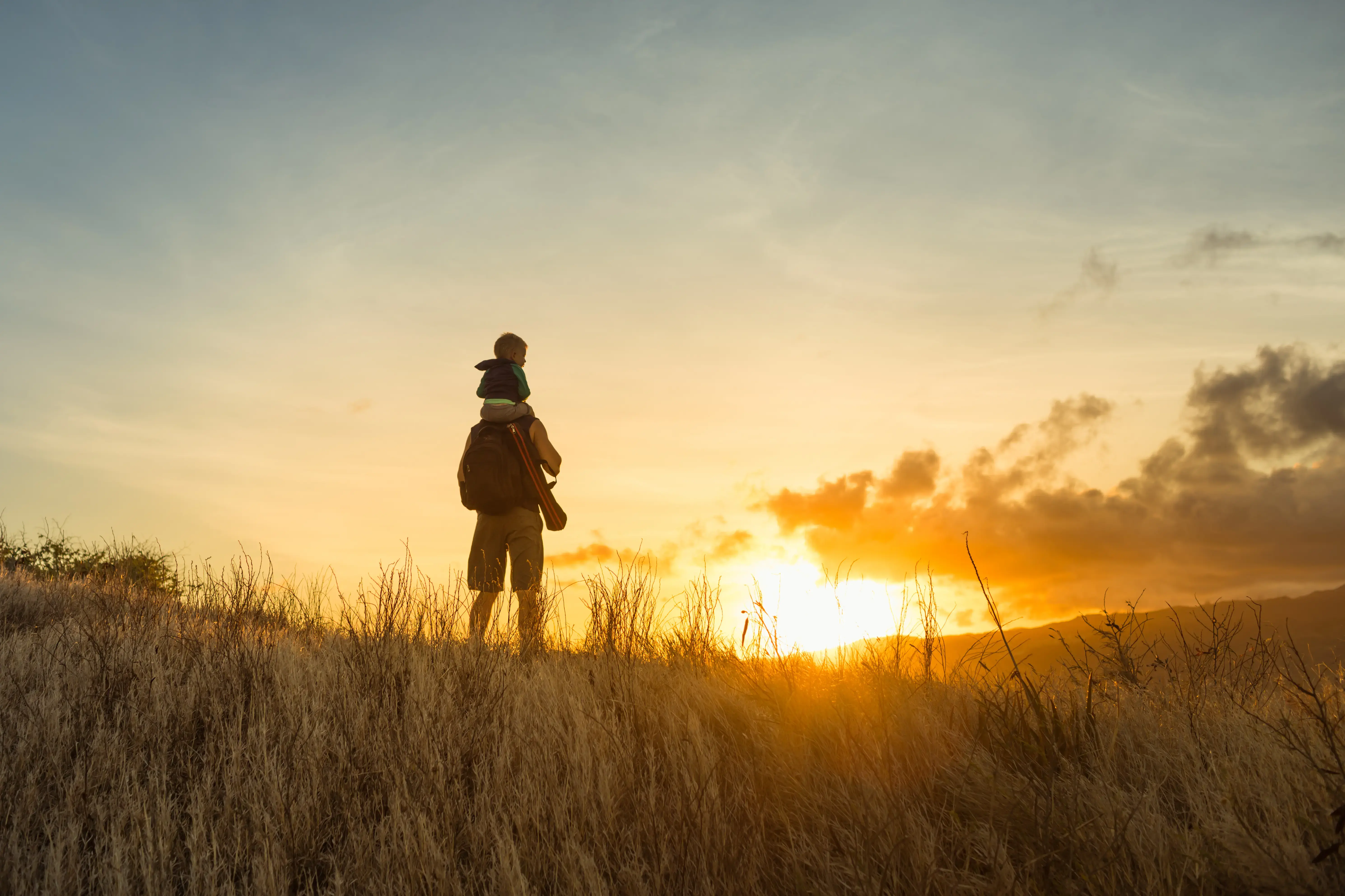 Father and son hiking through the mountain at sunrise