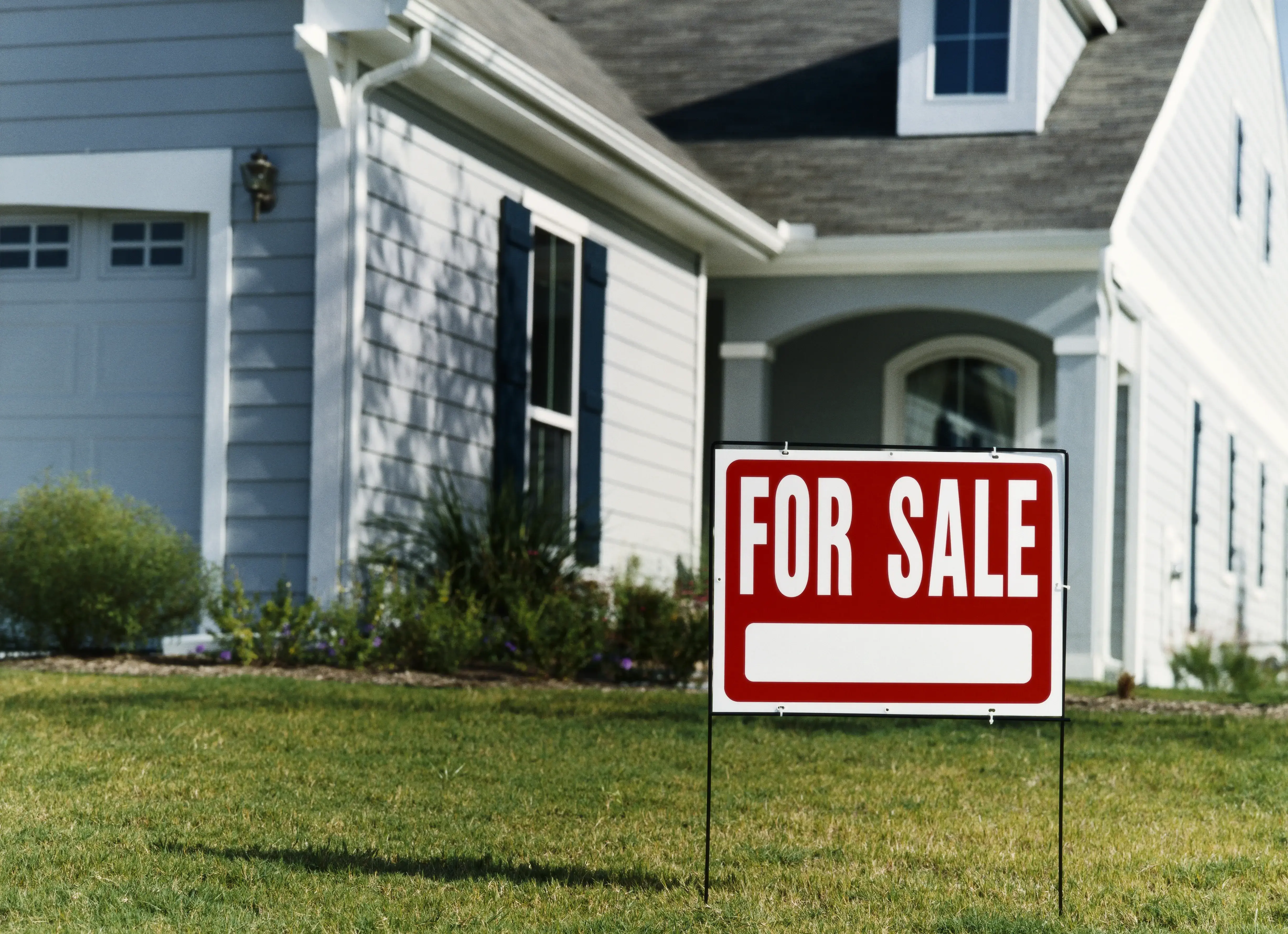 For Sale Sign in Front of a House on a Lawn