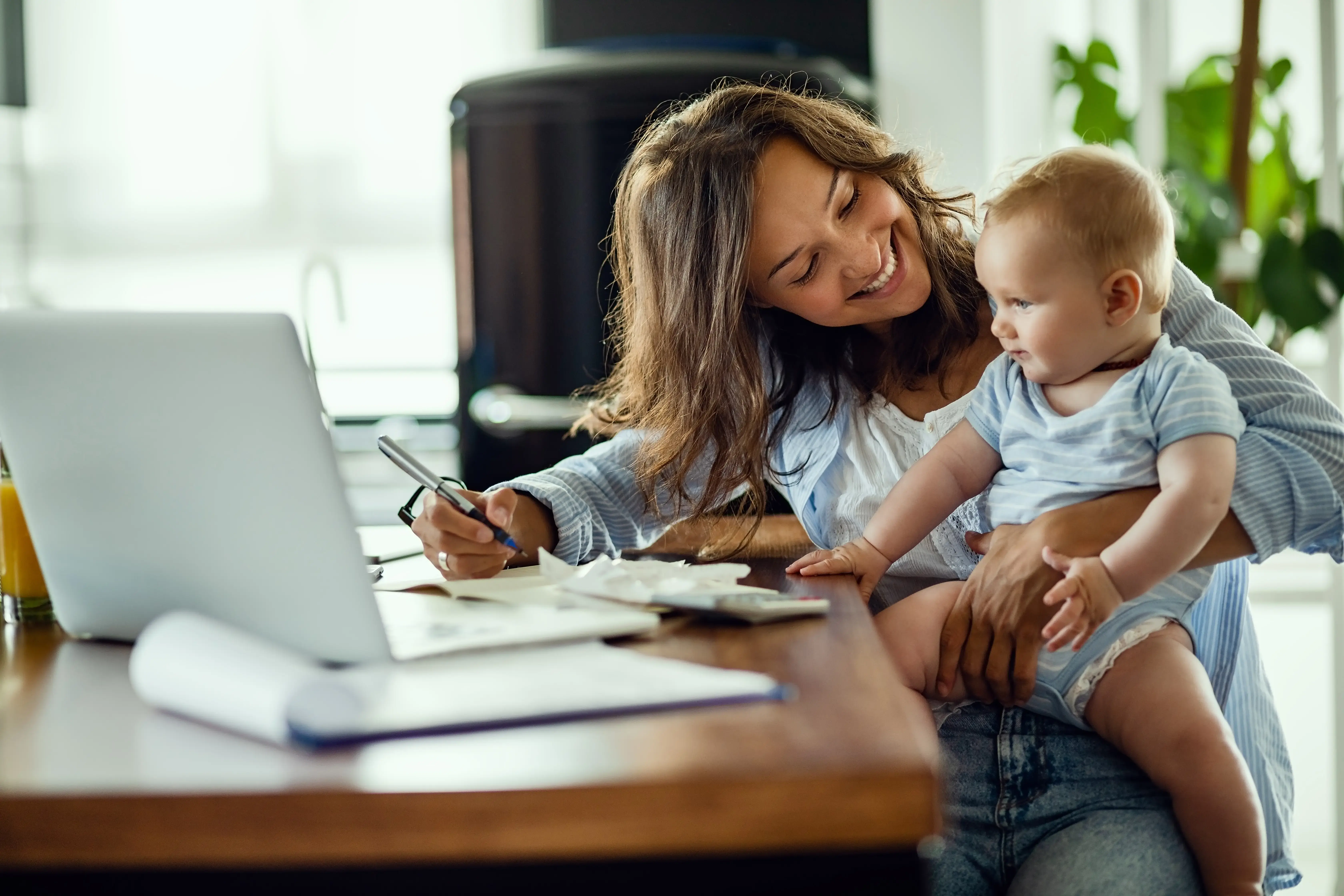 Happy mother talking to her baby while working at home.