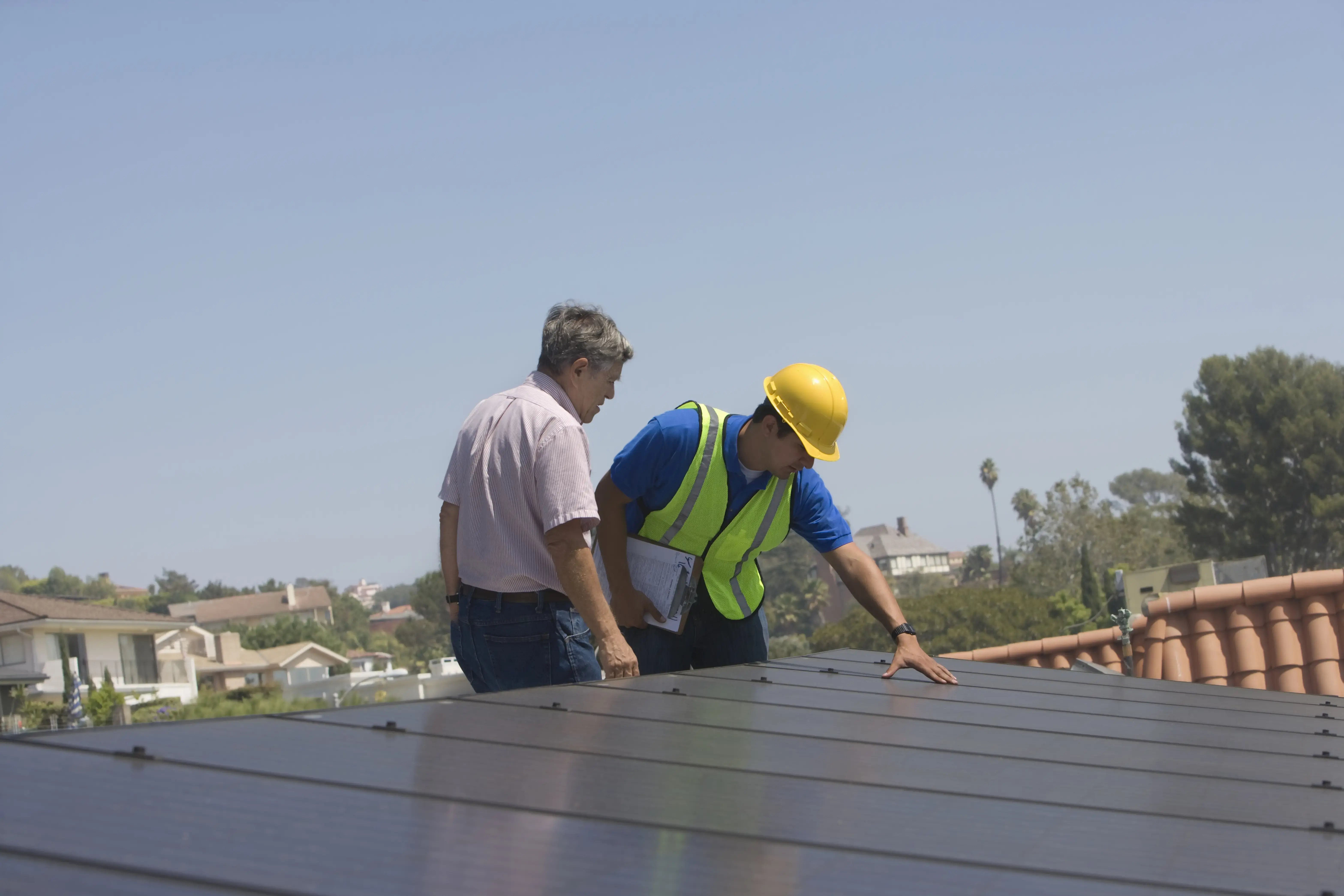 Maintenance workers stand with solar array on rooftop in Los Angeles, California