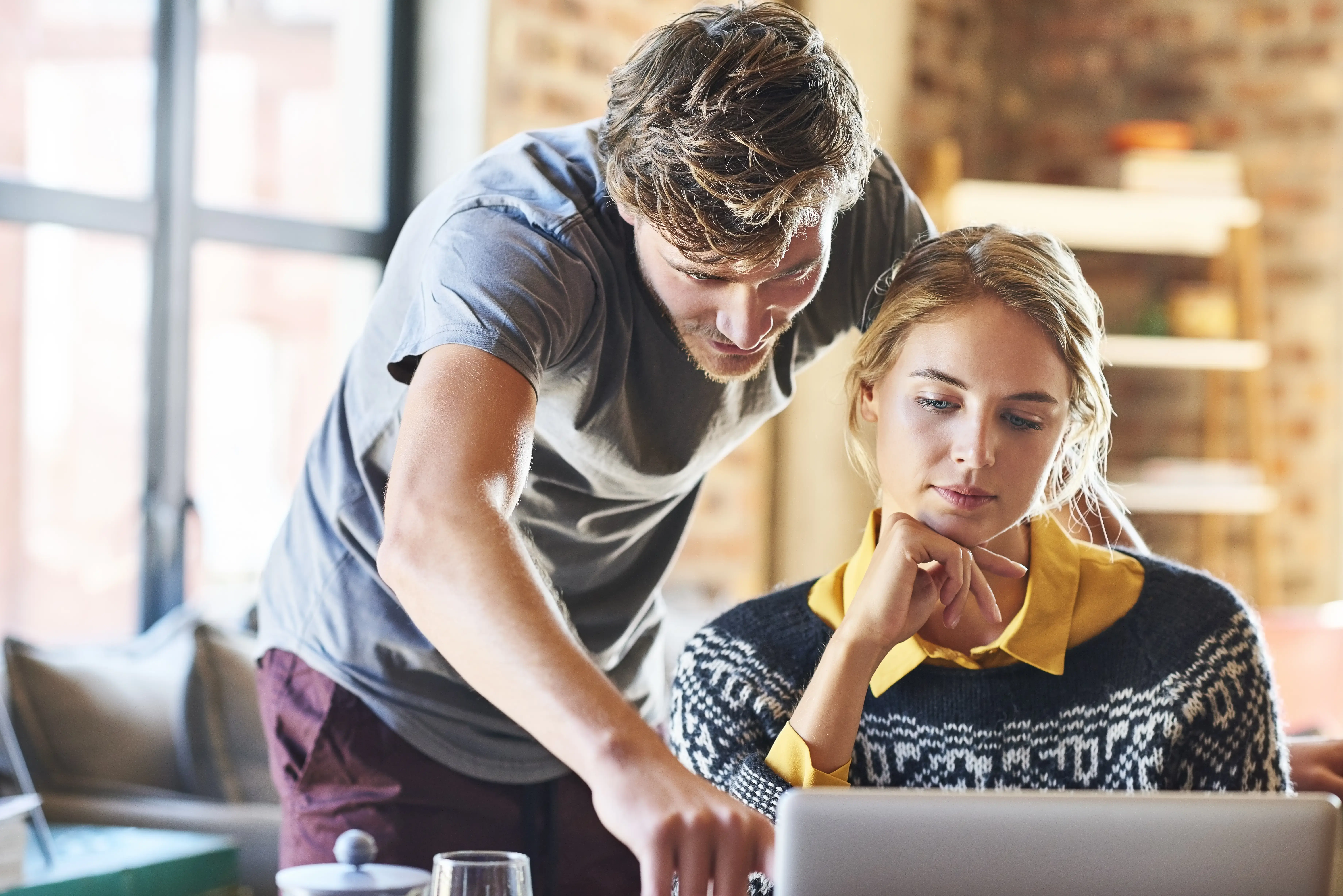 Man showing something on laptop to woman at home