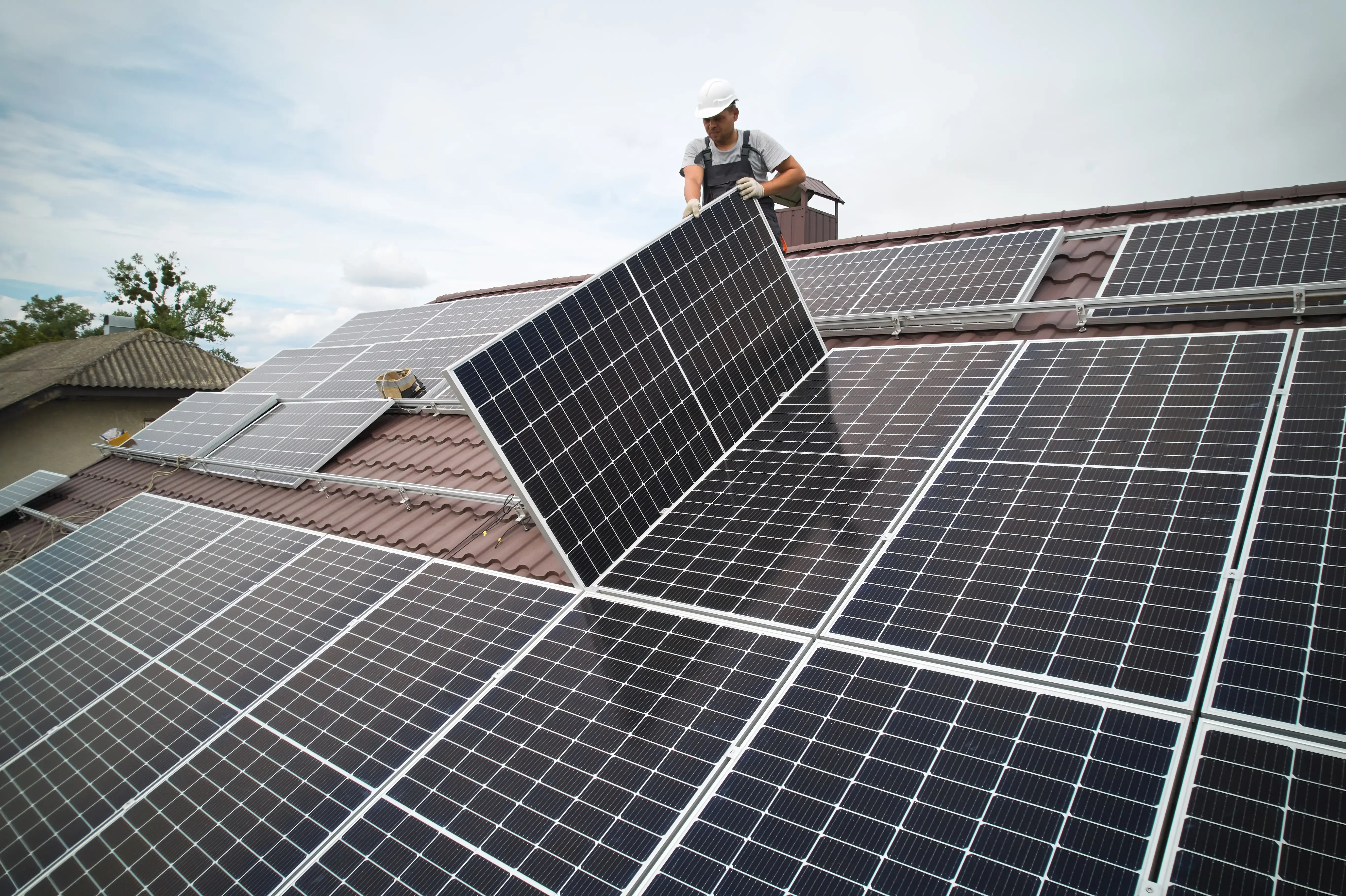 Men technicians mounting photovoltaic solar moduls on roof of house.