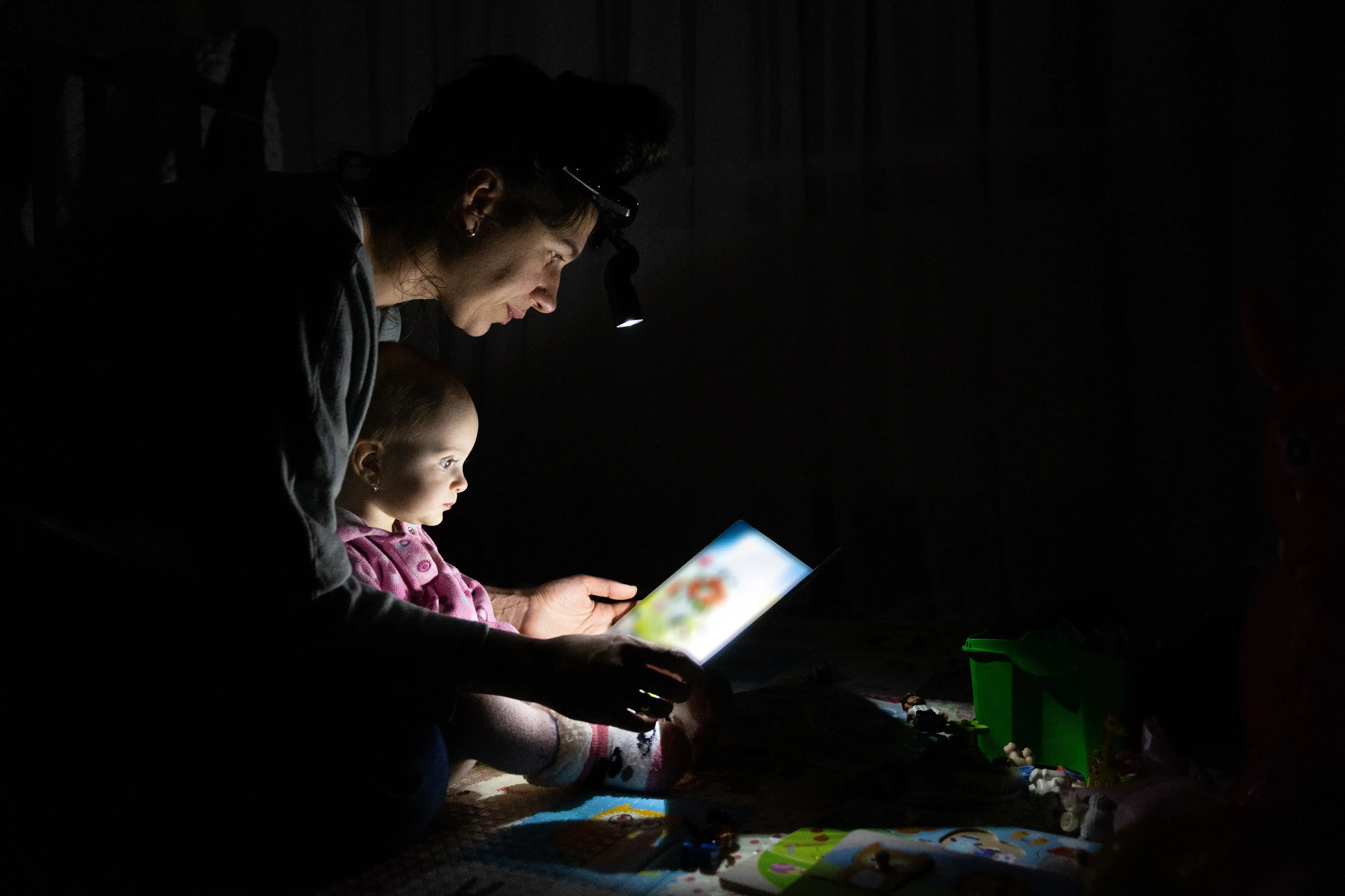 Mother reads a book to her daughter in the dark.